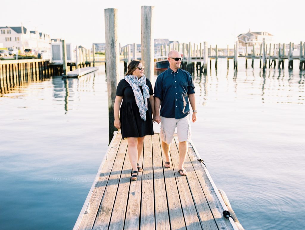 Engaged couple walking on dock of yacht club during Watch Hill Engagement session