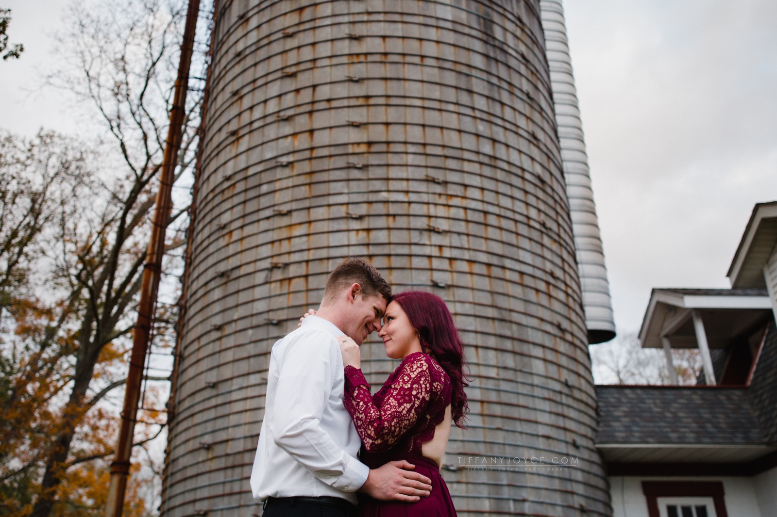 Couple embracing in front of silo during fox farm brewery engagement session